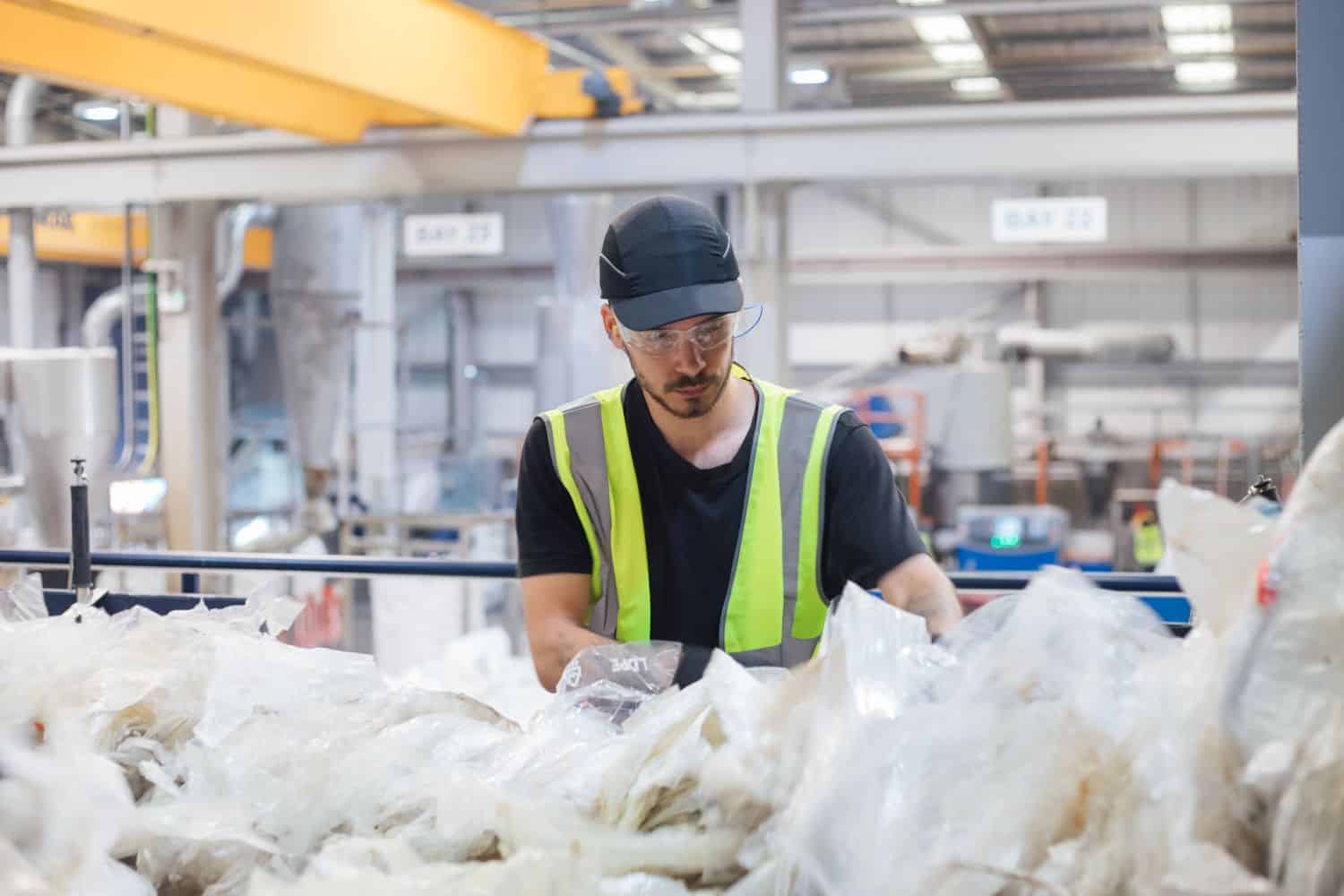 Duclo worker sorting through waste plastic bags